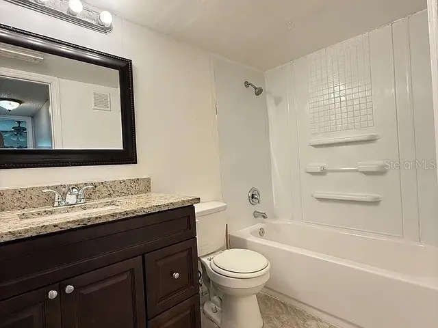 a bathroom with a granite countertop sink toilet a mirror and shower