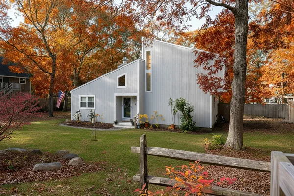 a view of a white house with a yard and a large tree