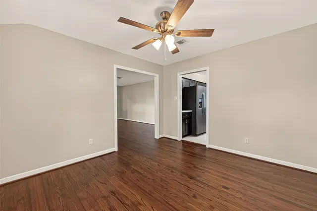 an empty room with wooden floor and a ceiling fan