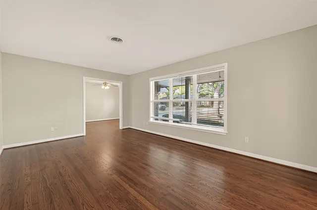 a view of an empty room with wooden floor and a window