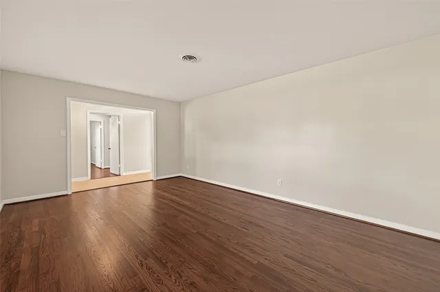 a view of an empty room with wooden floor and windows