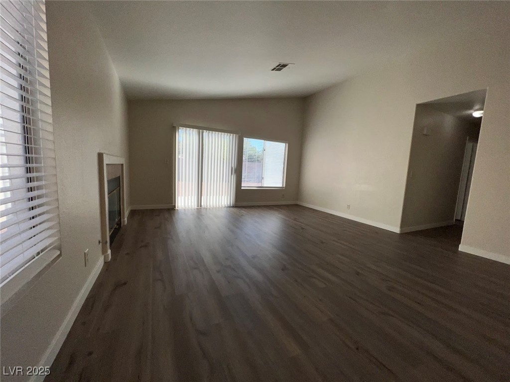 635 Delorean Drive North Las Vegas, NV 89081 - Photo 20 of 22 Unfurnished living room with lofted ceiling, dark wood finished floors, and a glass covered fireplace