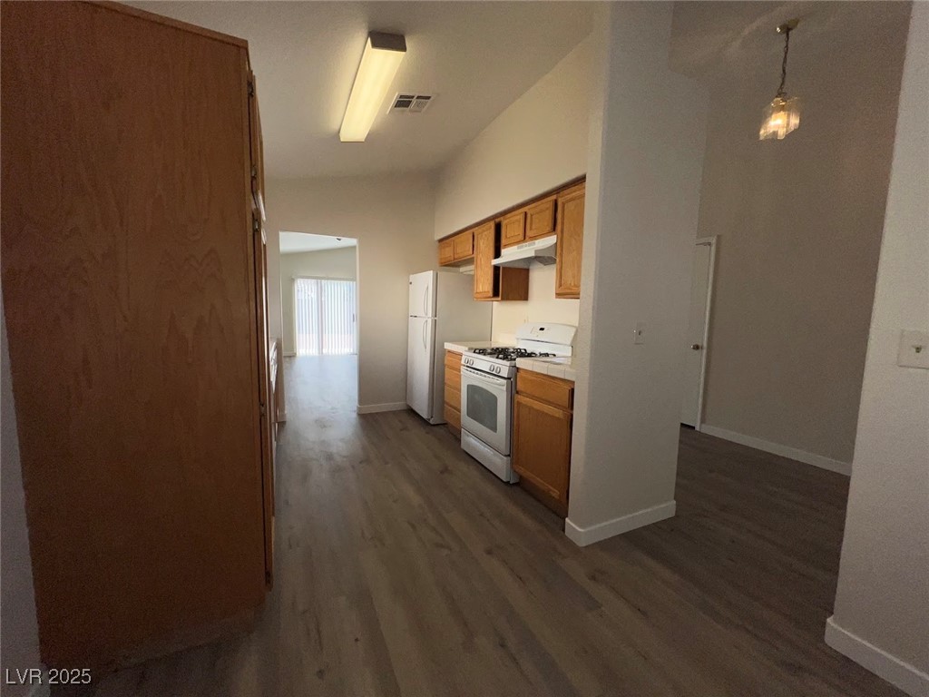 635 Delorean Drive North Las Vegas, NV 89081 - Photo 3 of 22 Kitchen with white gas range, light countertops, brown cabinetry, and dark wood finished floors