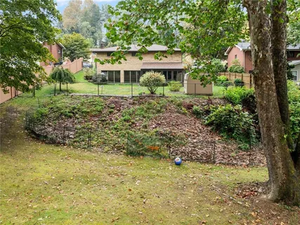 a view of a wooden house with a yard and large trees