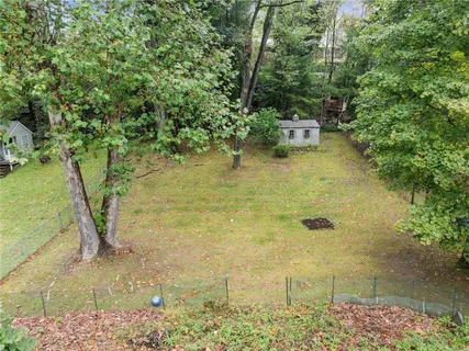 an aerial view of a house with a yard and trees all around