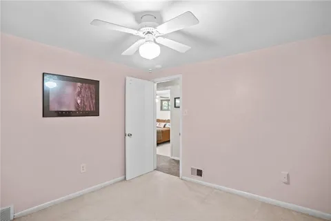 an empty room with a chandelier fan and windows