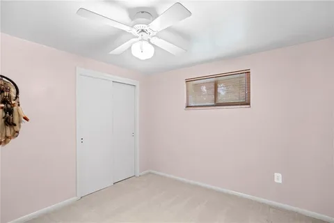 an empty room with a chandelier fan and windows