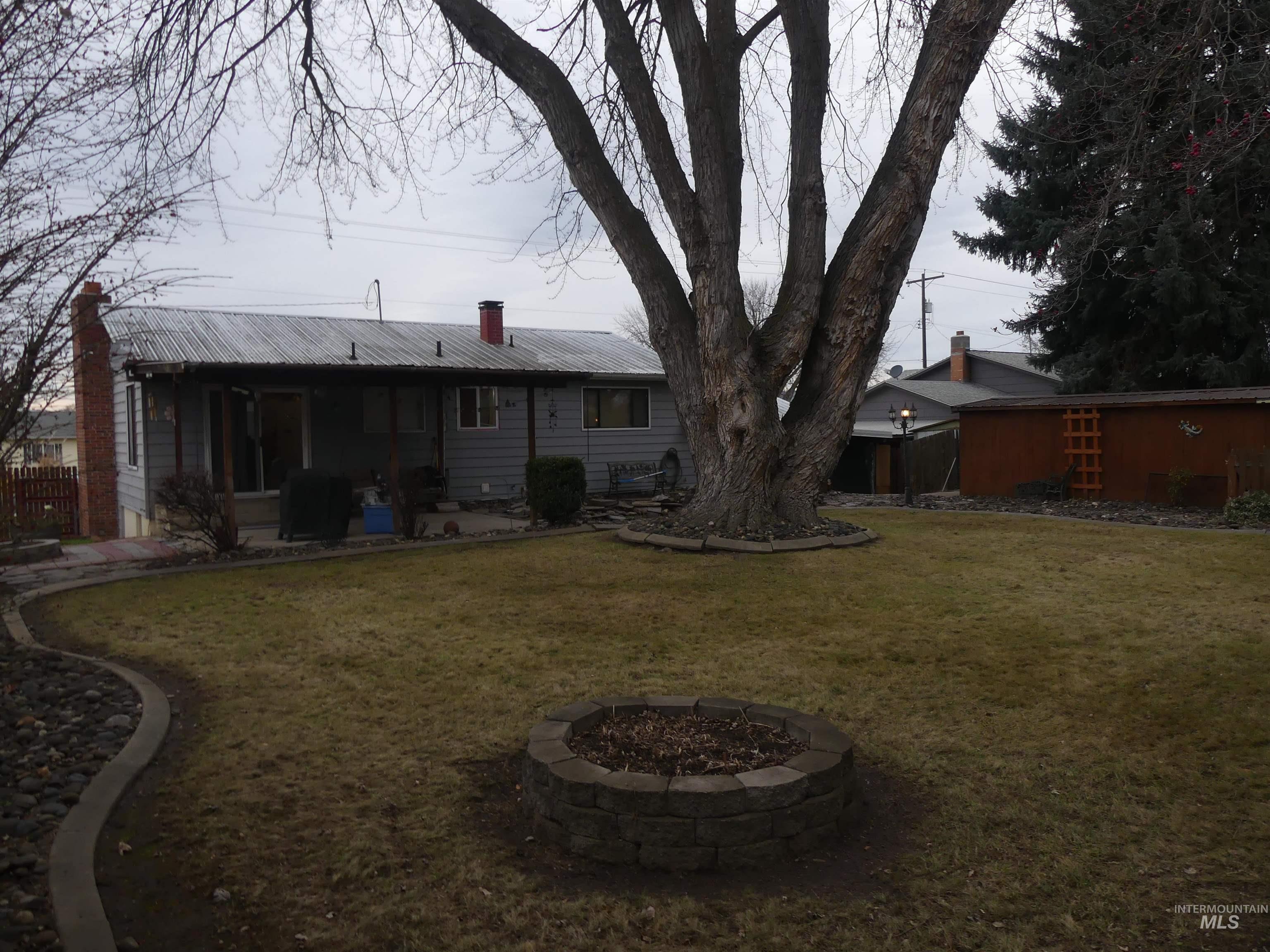 3427 18th Street Lewiston, ID 83501 - Photo 11 of 45 Back of property with a metal roof, an outdoor fire pit, a yard, a patio, and a chimney