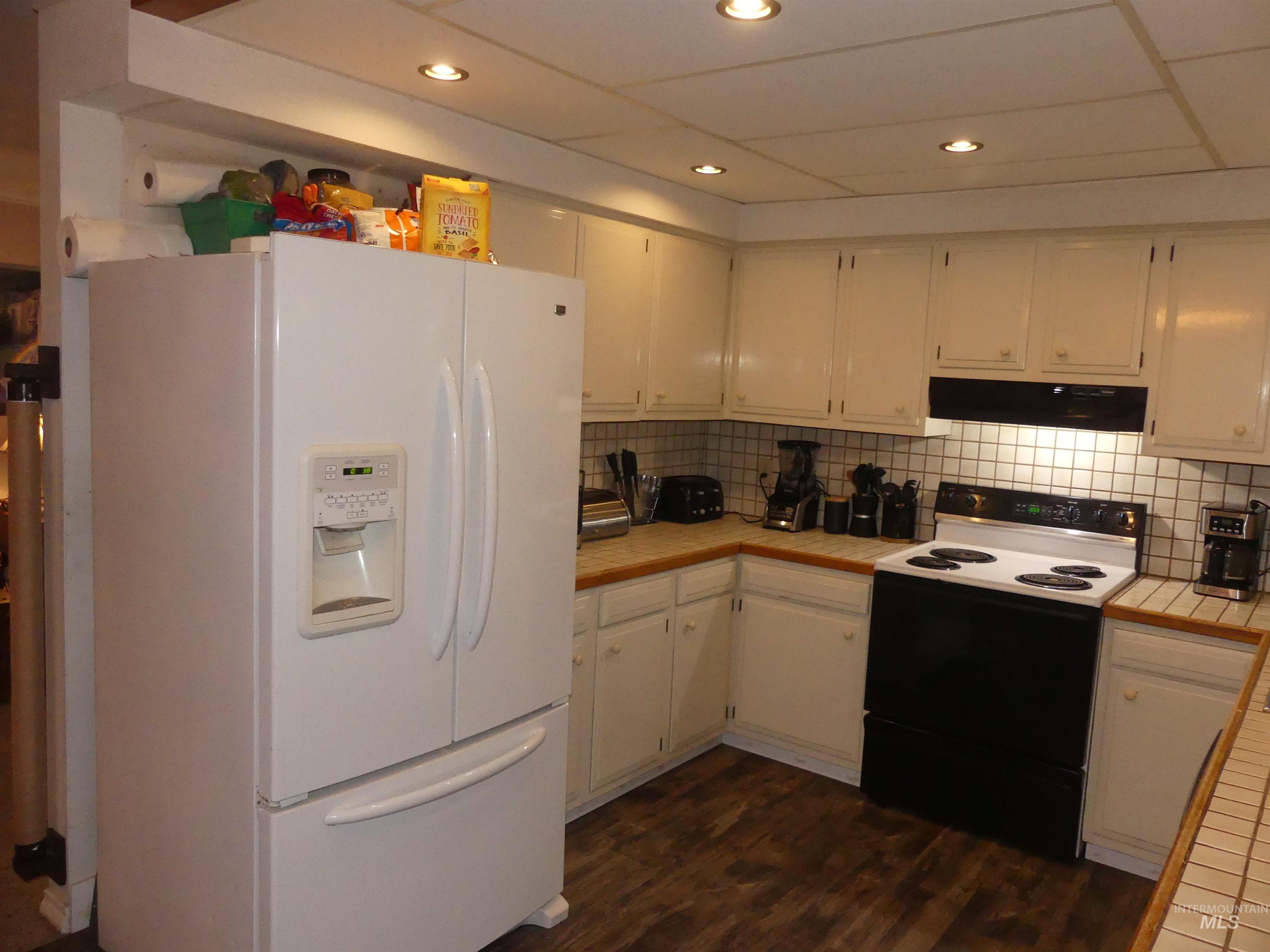 3427 18th Street Lewiston, ID 83501 - Photo 20 of 45 Kitchen featuring white refrigerator with ice dispenser, range with electric cooktop, white cabinets, tile countertops, and dark wood-style floors