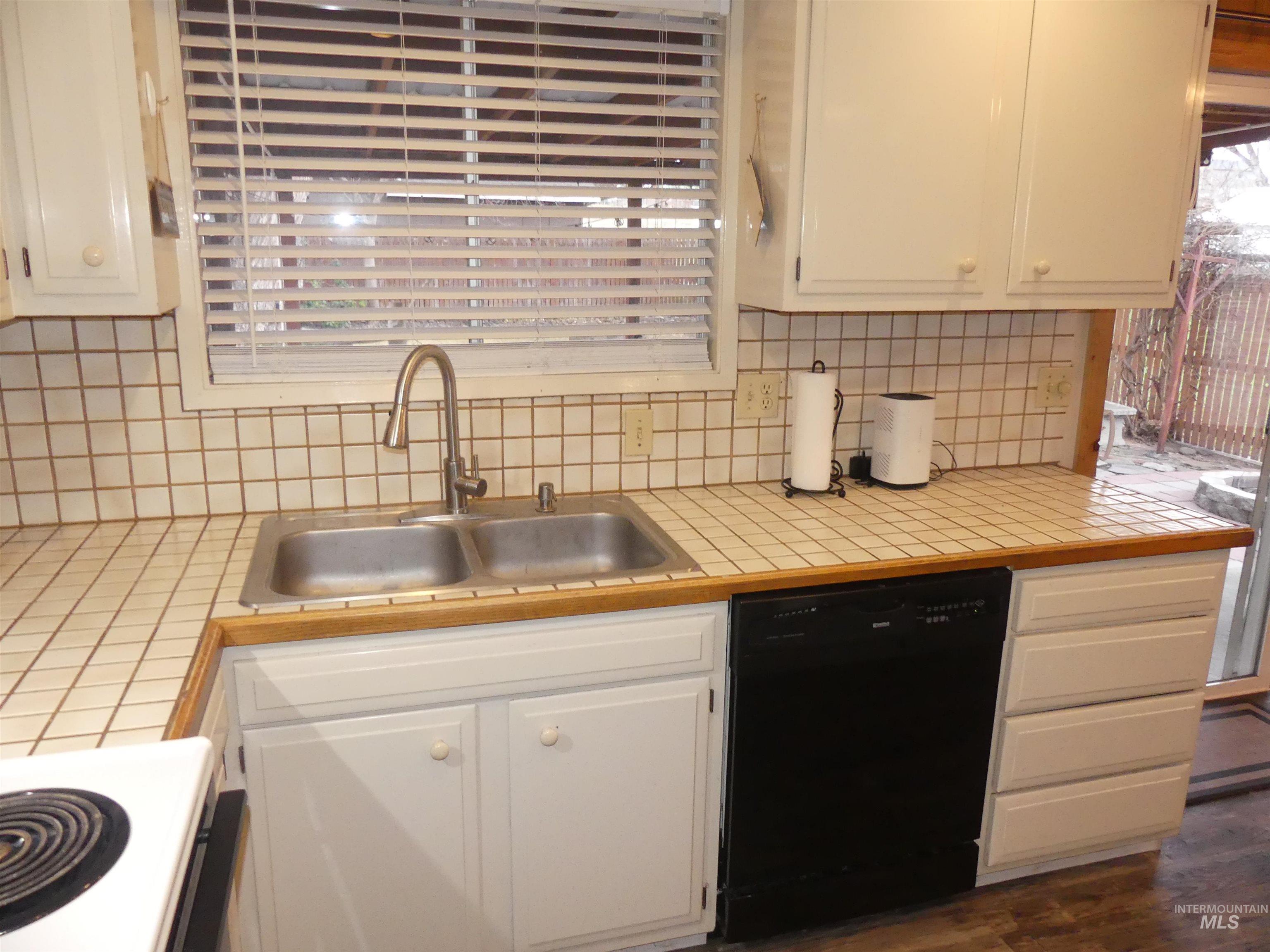 3427 18th Street Lewiston, ID 83501 - Photo 22 of 45 Kitchen with tile counters, black dishwasher, white electric range, tasteful backsplash, and white cabinets
