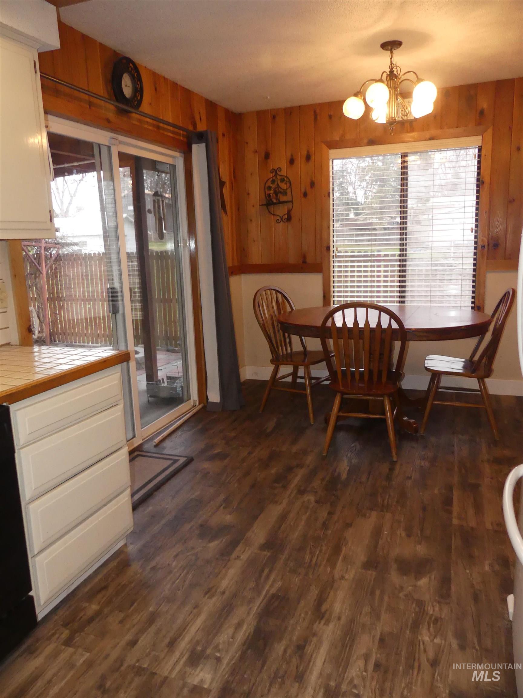 3427 18th Street Lewiston, ID 83501 - Photo 23 of 45 Dining room featuring healthy amount of natural light, dark wood-type flooring, wooden walls, and a chandelier