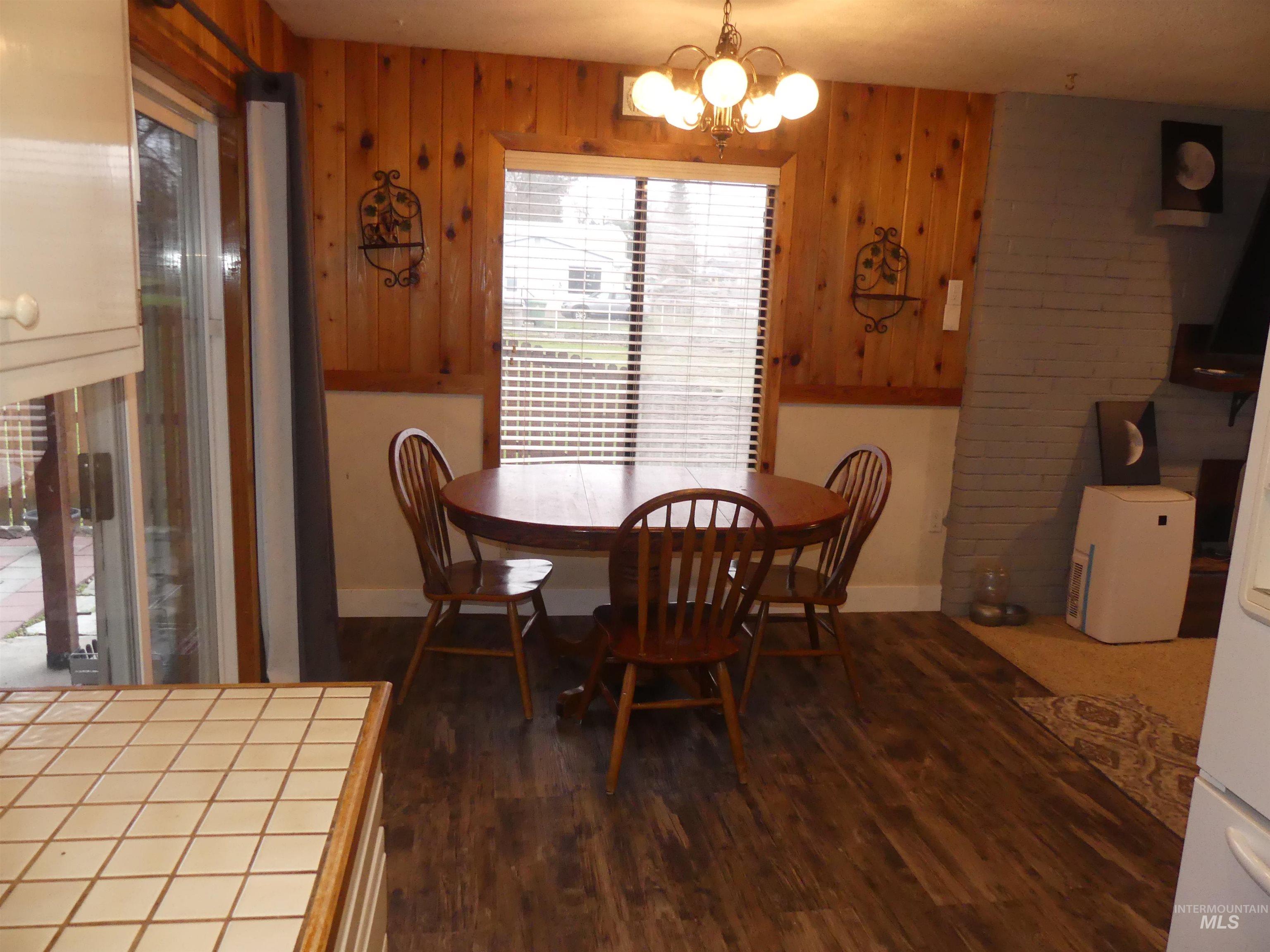 3427 18th Street Lewiston, ID 83501 - Photo 24 of 45 Dining area with dark wood-type flooring, a chandelier, and wooden walls