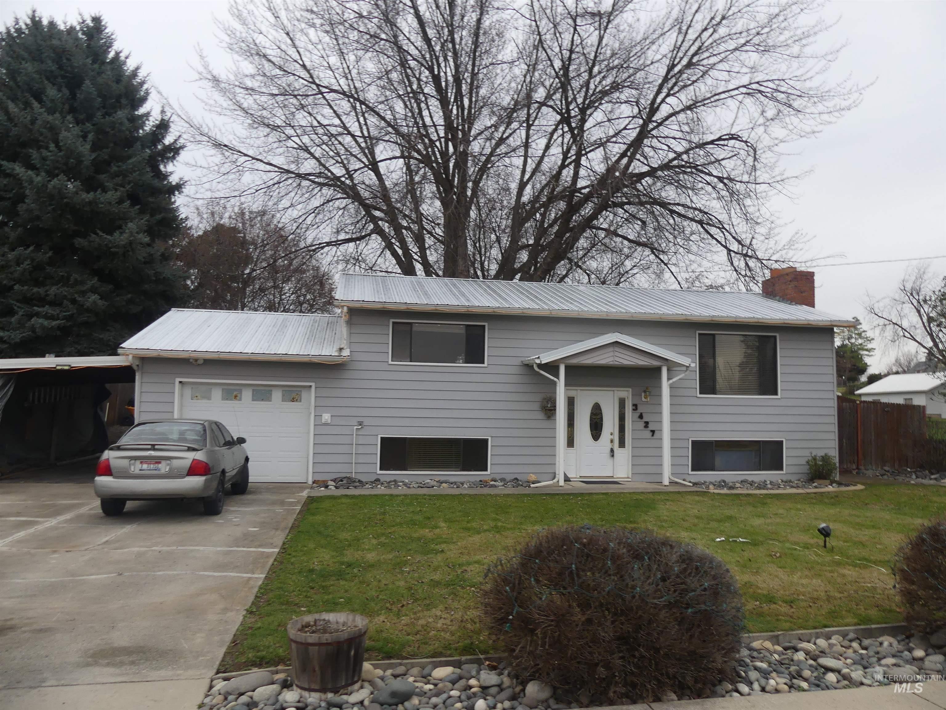 3427 18th Street Lewiston, ID 83501 - Photo 39 of 45 Raised ranch featuring concrete driveway, a chimney, an attached garage, a metal roof, and a carport