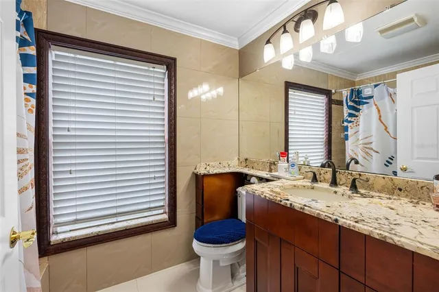 a bathroom with a granite countertop sink toilet and mirror