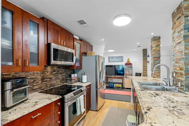 a kitchen with stainless steel appliances granite countertop a stove top oven a sink dishwasher a dining table and chairs with wooden floor