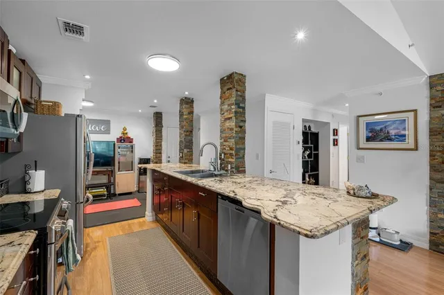 a kitchen with stainless steel appliances granite countertop a sink and a refrigerator