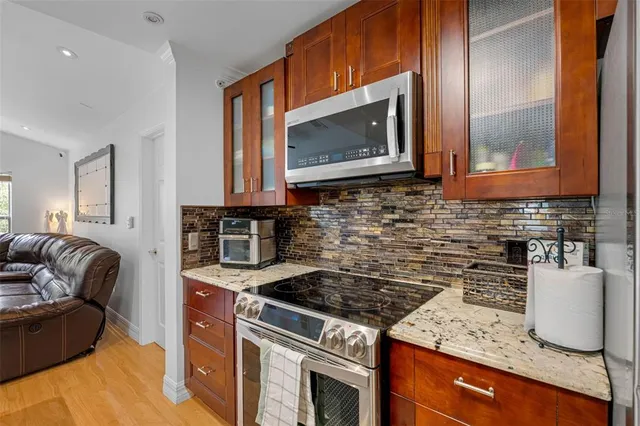 a kitchen with granite countertop a stove top oven microwave and cabinets
