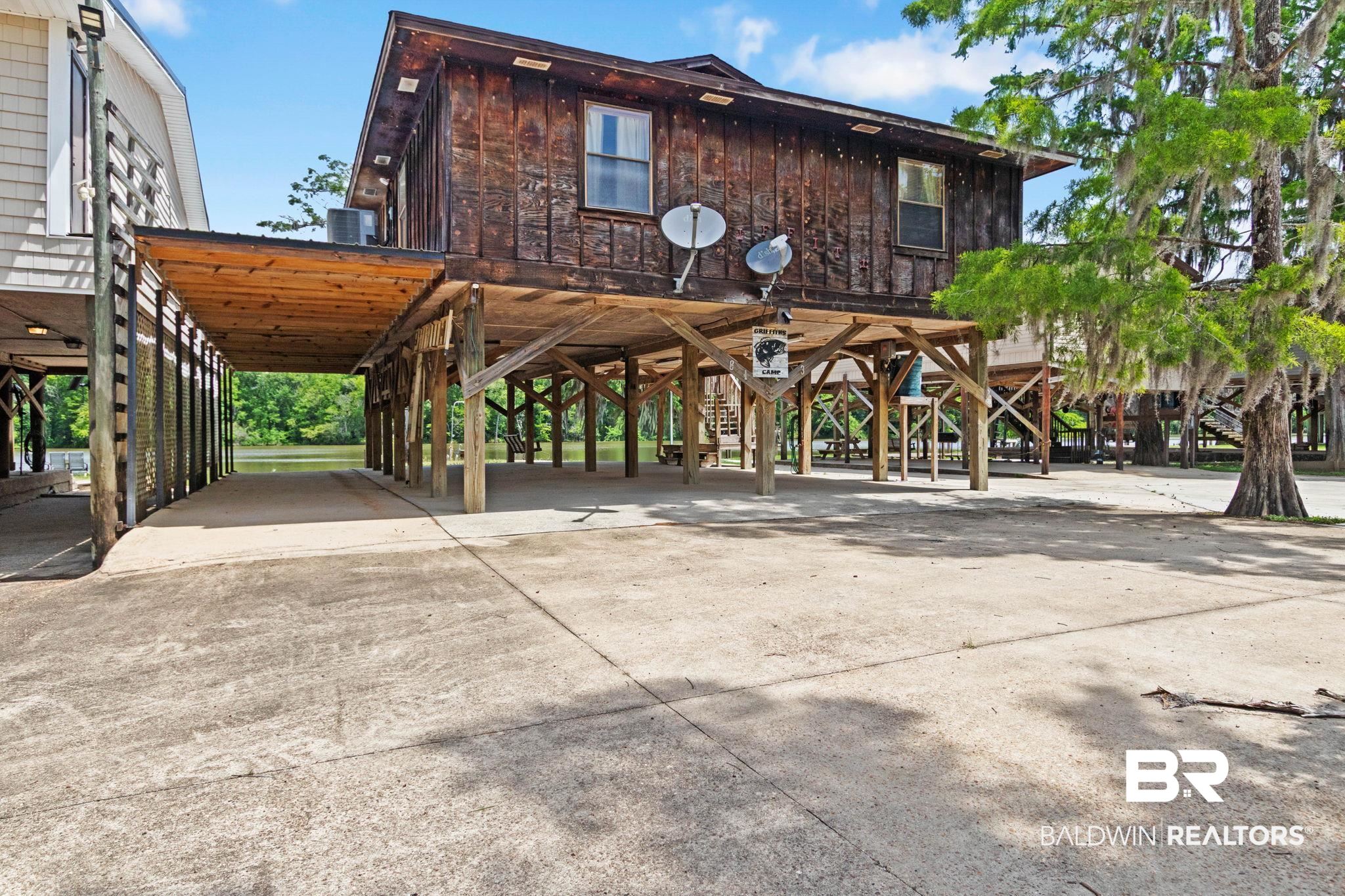 8153 Bryant's Lndg Road Stockton, AL 36579 - Photo 13 of 87 Elevated wood-sided residence featuring a covered boat slip, reinforced pilings, and a concrete drive