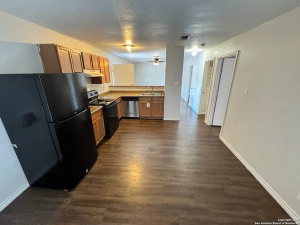 a kitchen with granite countertop a refrigerator a sink a stove a microwave a counter space and cabinets