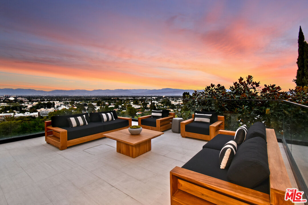 a view of a roof deck with couches and sky view