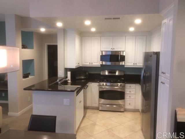 a kitchen with kitchen island granite countertop stainless steel appliances a stove a sink and a refrigerator
