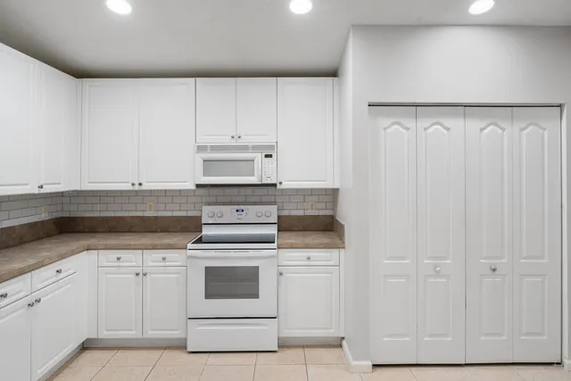 a kitchen with white cabinets and white appliances