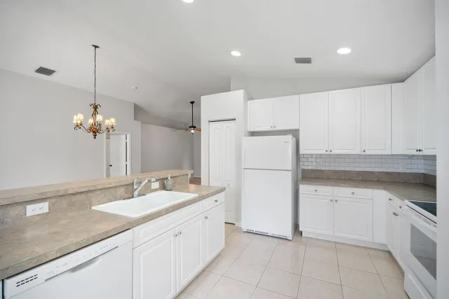 a kitchen with a sink dishwasher a refrigerator and white cabinets with wooden floor