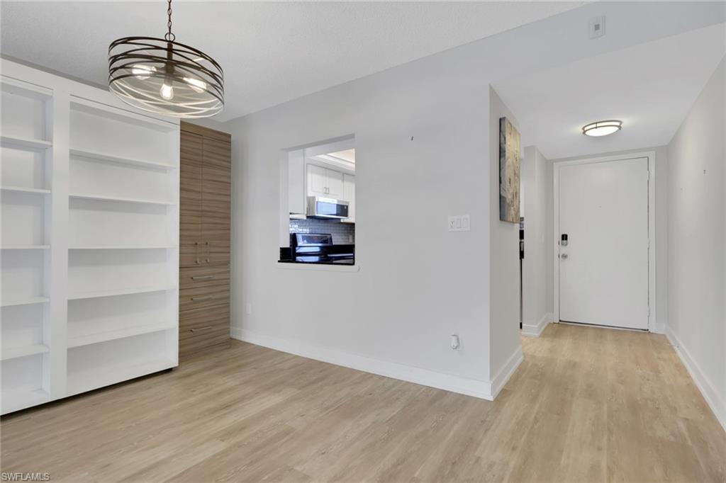 5499 Rattlesnake Hamm Road, Unit A207 Naples, FL 34113 - Photo 6 of 32 a view of empty room with wooden floor and cabinet