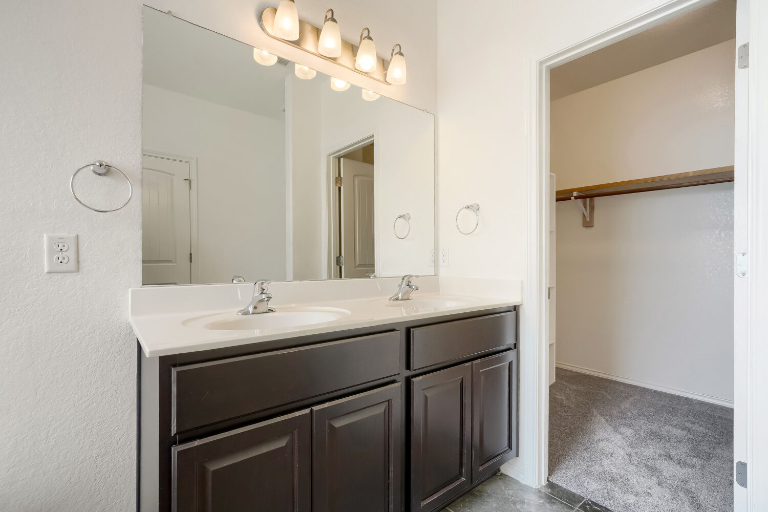 2420 Ranger Pass Seguin, TX 78155 - Photo 16 of 28 Double vanity with white countertop, chrome fixtures, dark wood-finish cabinetry, and overhead lighting