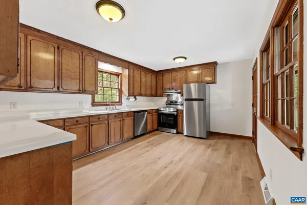 a kitchen with stainless steel appliances granite countertop a stove a sink dishwasher a refrigerator and a microwave oven with wooden floor