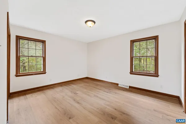 a view of an empty room with a window and wooden floor