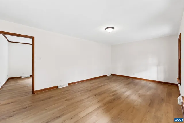a view of an empty room with wooden floor fireplace and a window