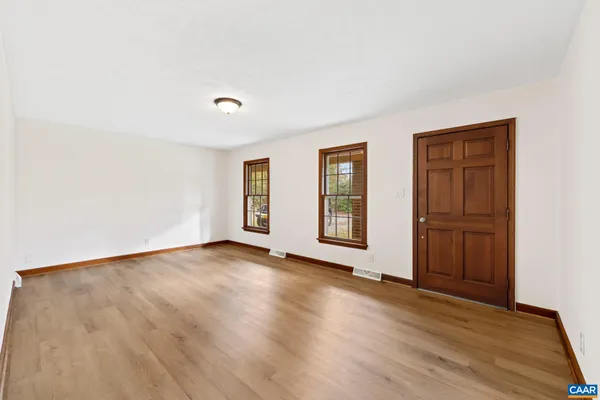 a view of an empty room with window and wooden floor