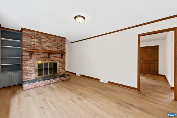 an empty room with wooden floor fireplace and windows