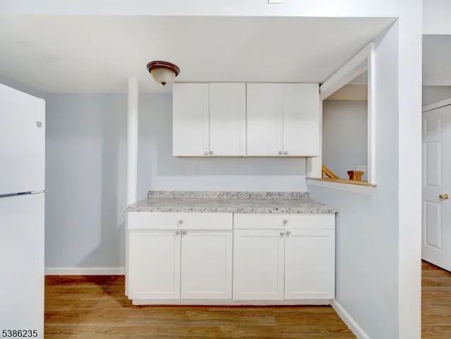 a view of a kitchen with white cabinets and a refrigerator