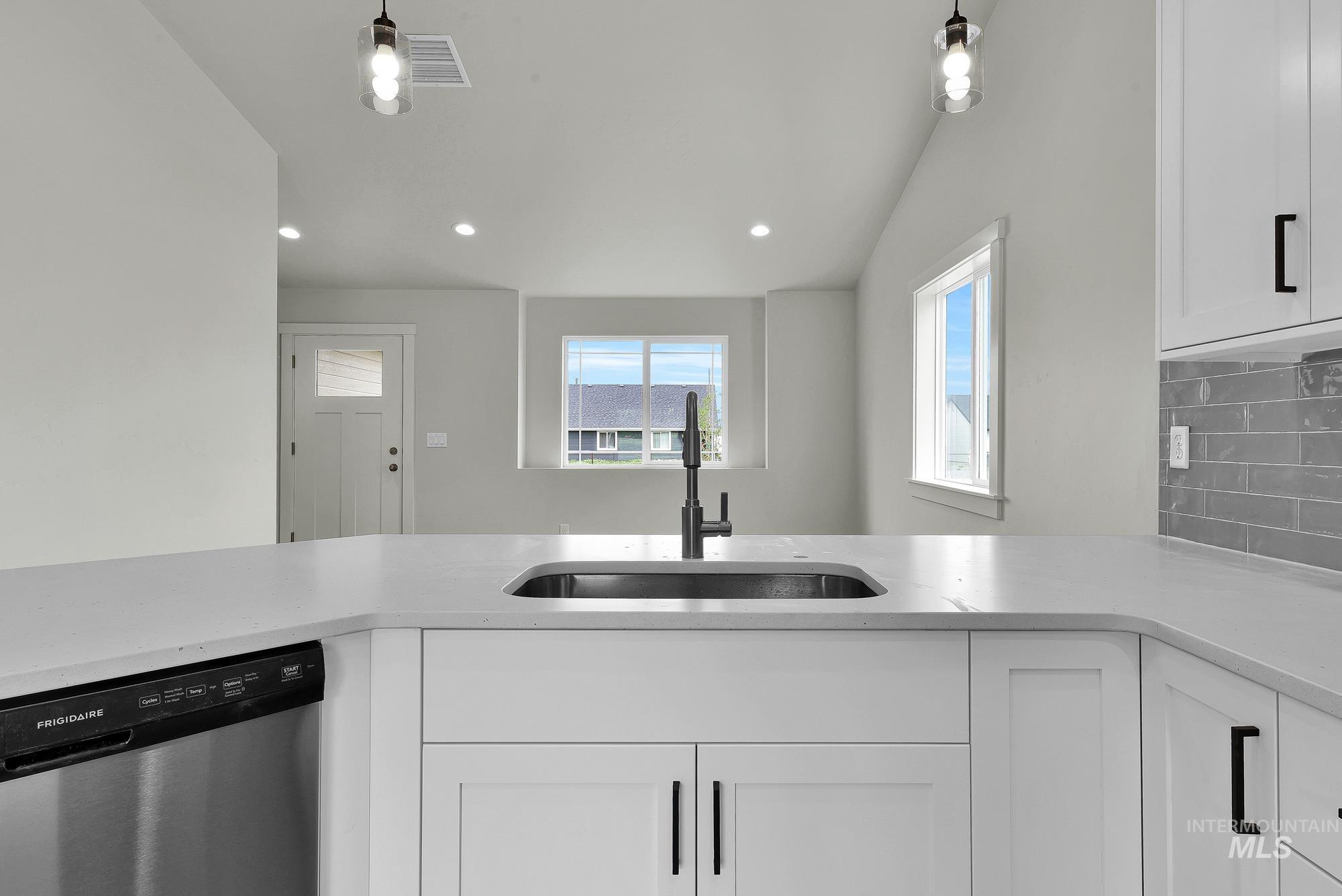 328 Packer Lane Homedale, ID 83628 - Photo 11 of 25 Kitchen with white cabinetry, dishwasher, tasteful backsplash, light stone counters, and vaulted ceiling