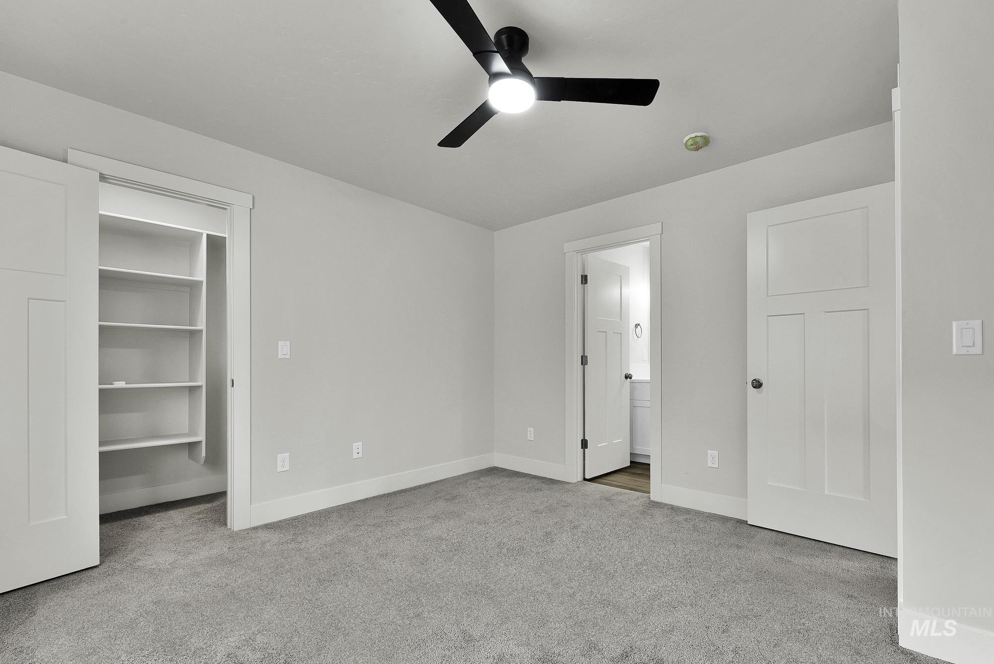 328 Packer Lane Homedale, ID 83628 - Photo 13 of 25 Unfurnished bedroom featuring light carpet, a walk in closet, a ceiling fan, and connected bathroom