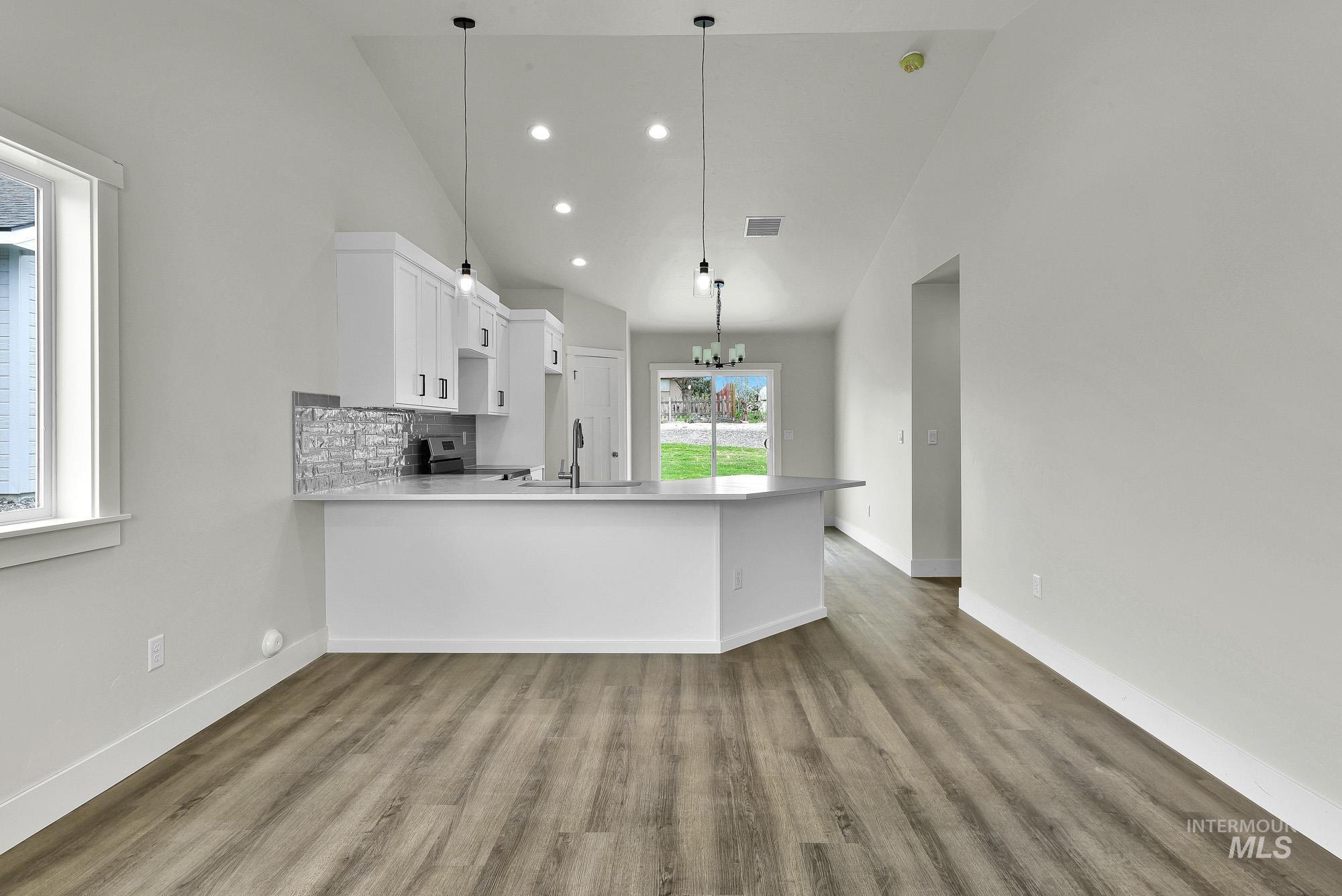 328 Packer Lane Homedale, ID 83628 - Photo 5 of 25 Kitchen with white cabinets, a peninsula, a chandelier, tasteful backsplash, and lofted ceiling