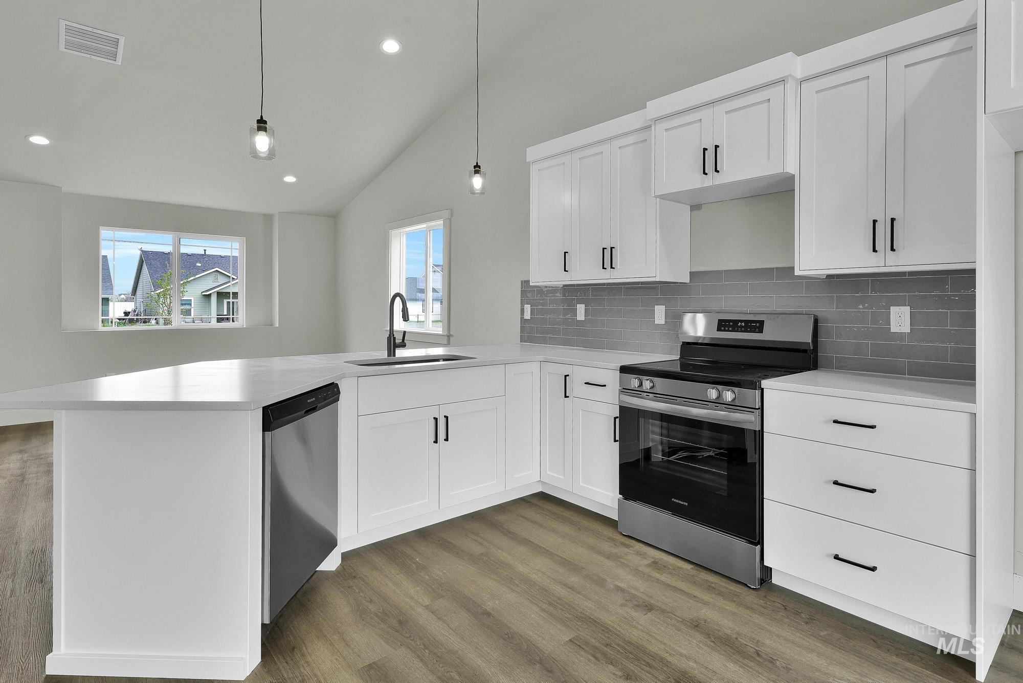 328 Packer Lane Homedale, ID 83628 - Photo 8 of 25 Kitchen with stainless steel appliances, vaulted ceiling, dark wood-type flooring, white cabinetry, and backsplash