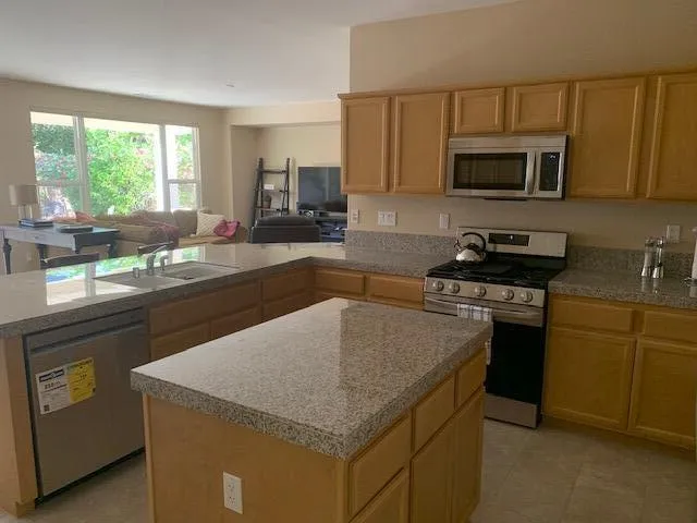 a kitchen with stainless steel appliances granite countertop a sink stove microwave and refrigerator
