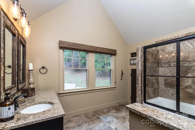 a bathroom with a granite countertop sink a mirror and next to a window