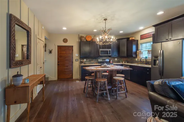 a kitchen with stainless steel appliances kitchen island granite countertop a table chairs and a refrigerator