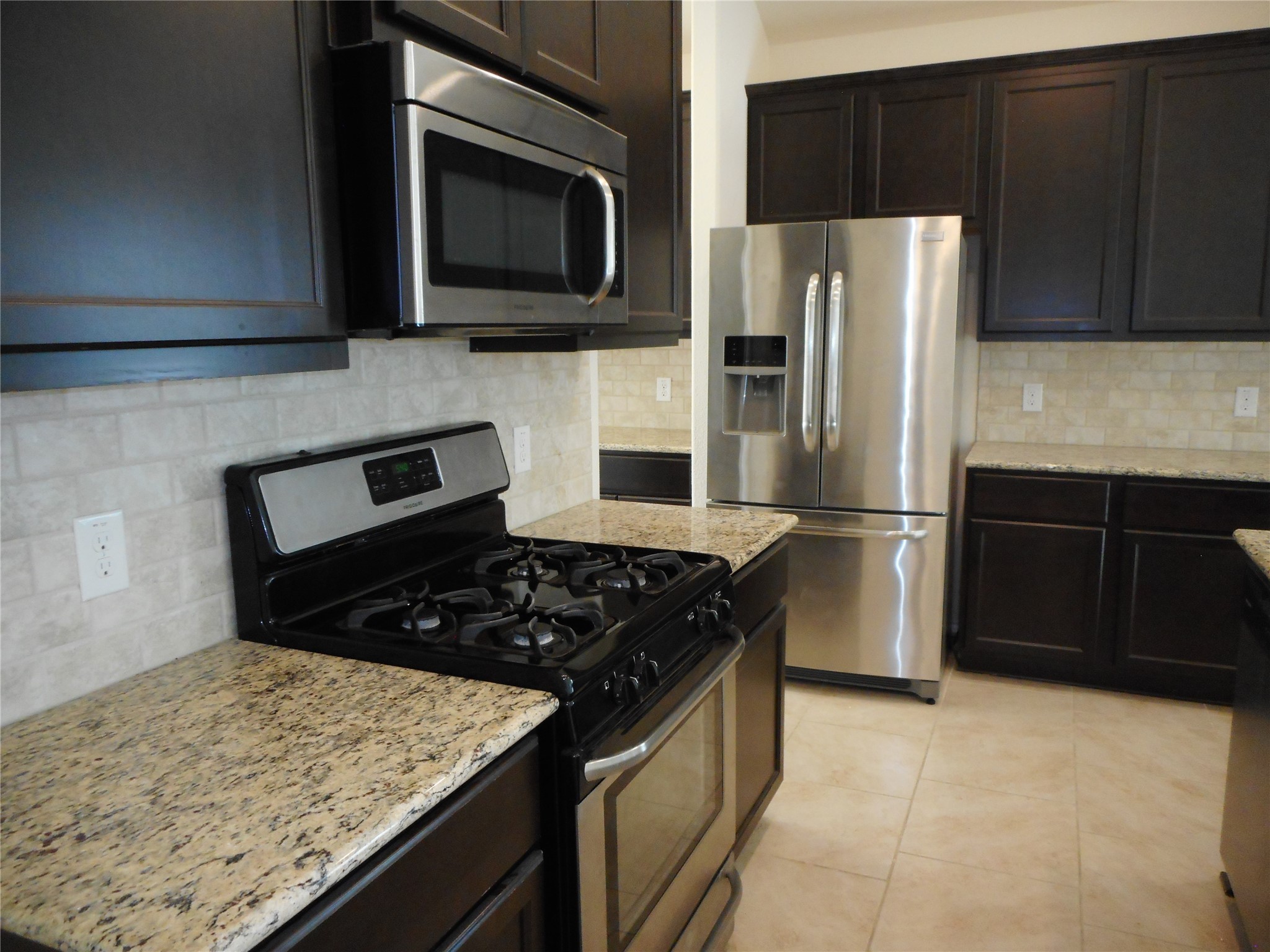 14021 Buffalo Gap Trail Conroe, TX 77384 - Photo 10 of 20 a kitchen with granite countertop a stove and a refrigerator
