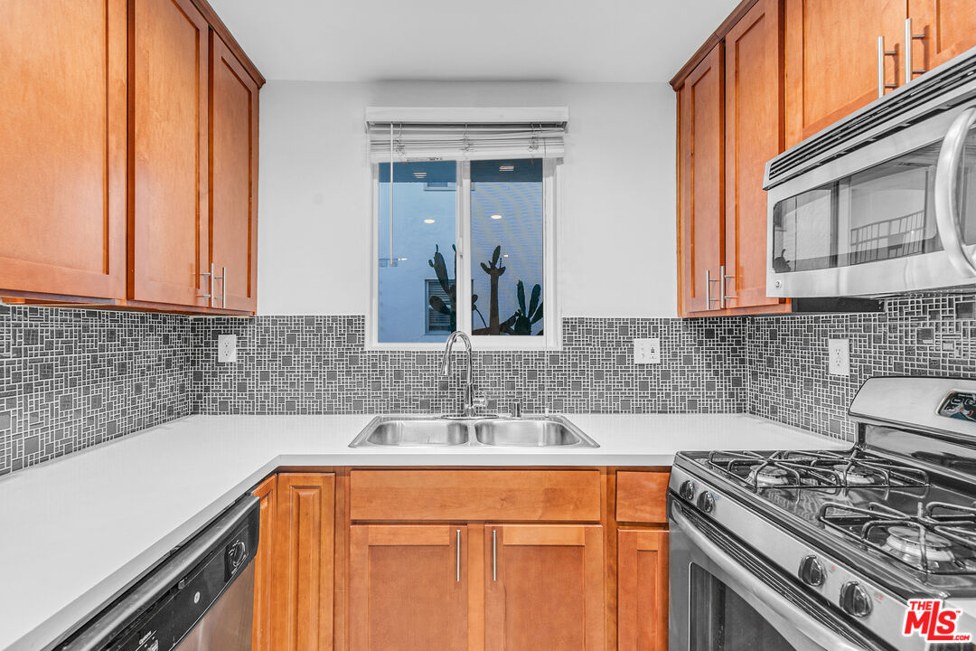 a kitchen with stainless steel appliances granite countertop a sink stove and cabinets