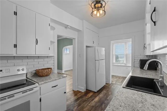 a kitchen with granite countertop a stove a sink and a refrigerator