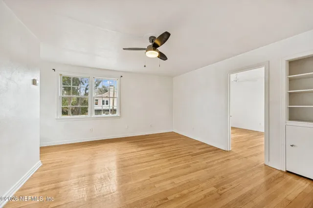 a view of empty room with wooden floor and fan