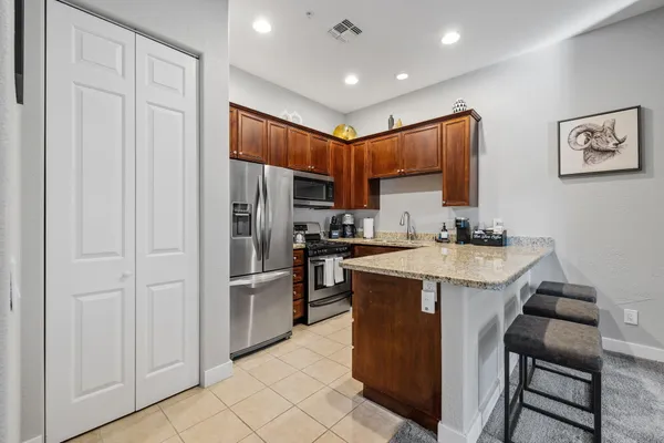 a kitchen with stainless steel appliances granite countertop a refrigerator a sink dishwasher and white cabinets with wooden floor