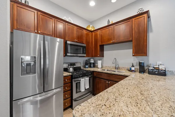 a kitchen with granite countertop a refrigerator stove and sink