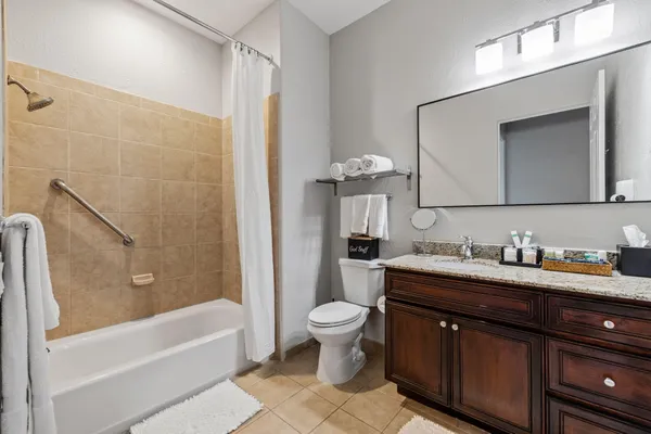a bathroom with a granite countertop sink a toilet a mirror and bathtub