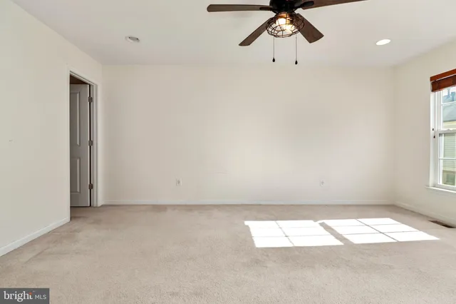 an empty room with a window and a ceiling fan
